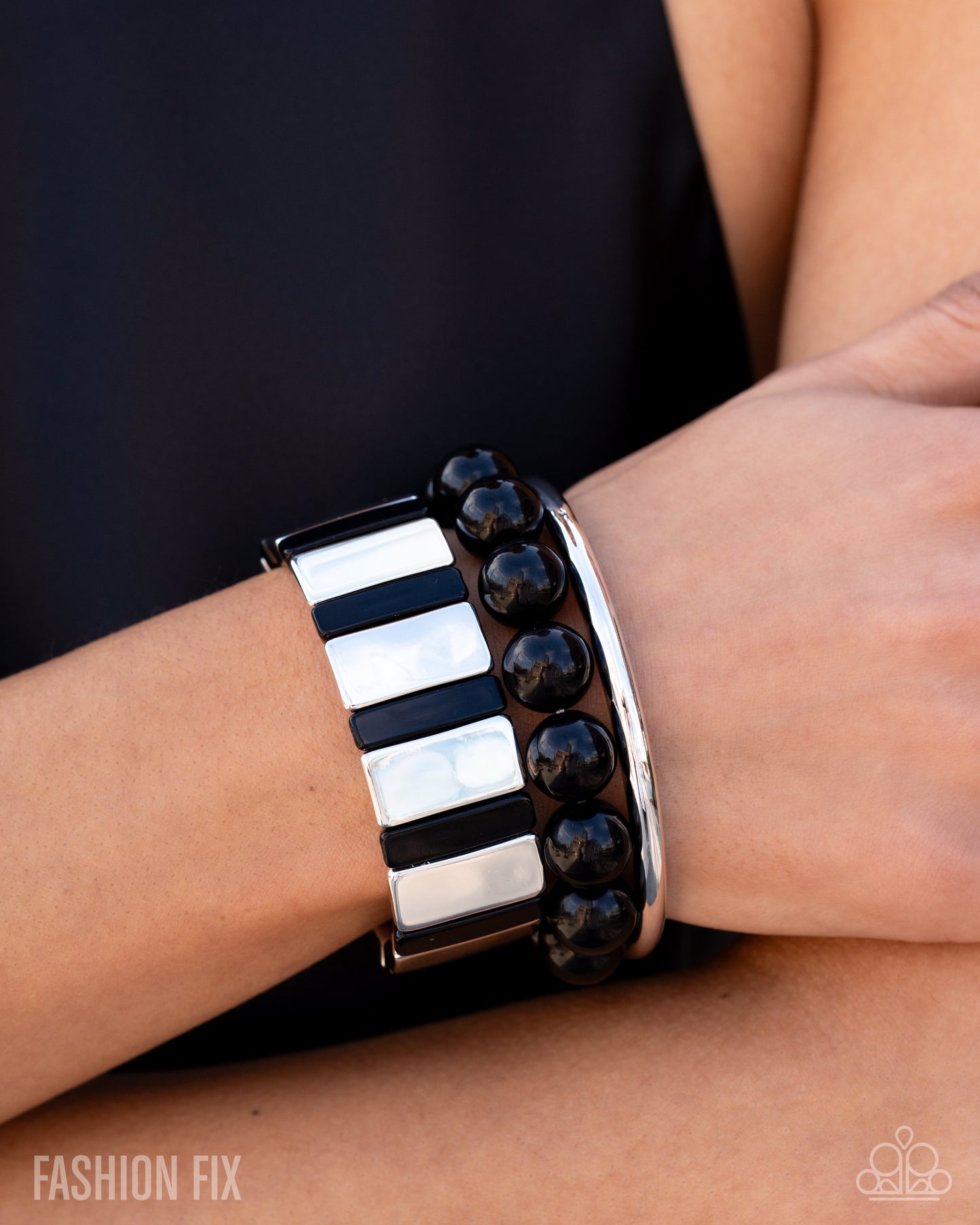 Close-up of a wrist wearing a black and white patterned bracelet with 'Fashion Fix' branding.