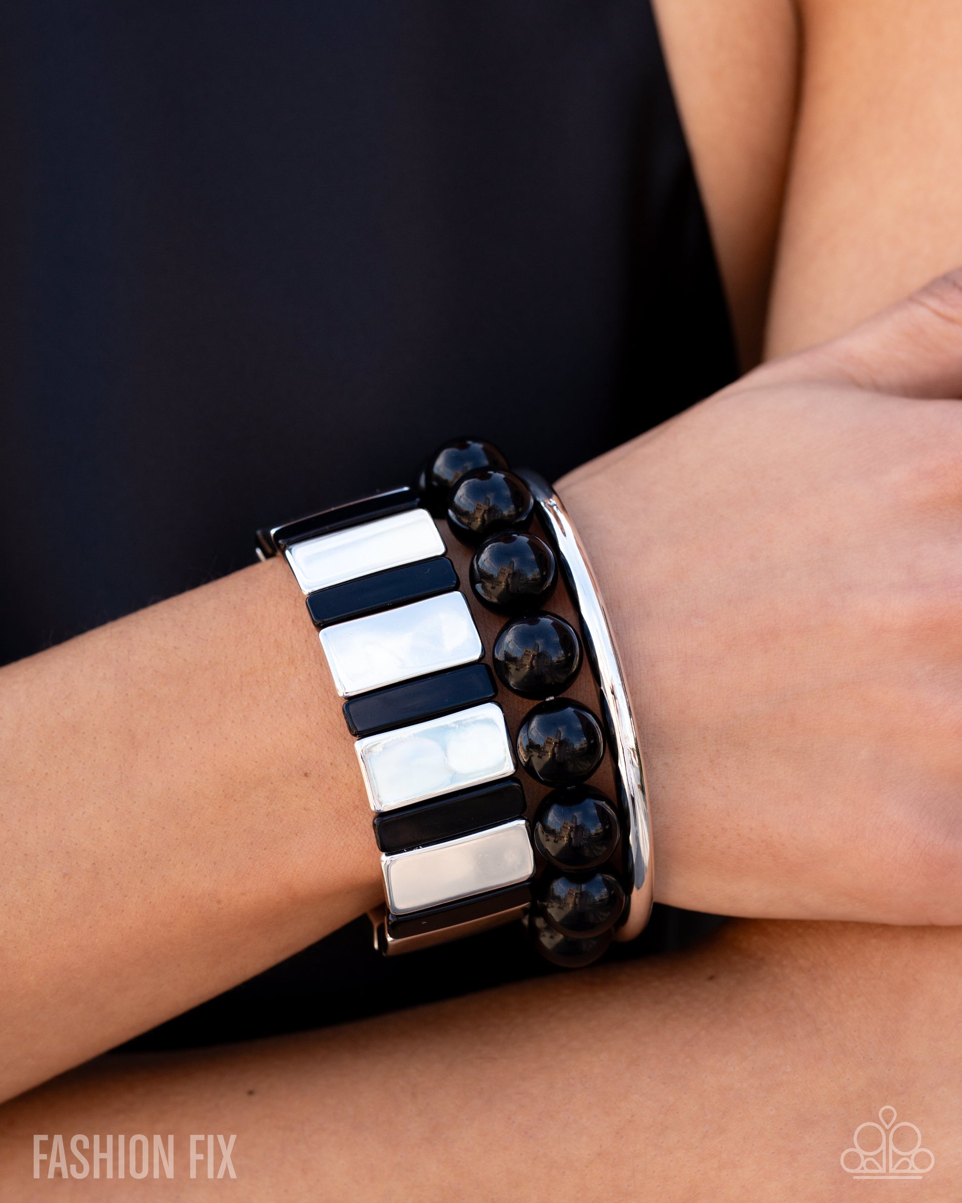 Close-up of a wrist wearing a black and white patterned bracelet with 'Fashion Fix' branding.