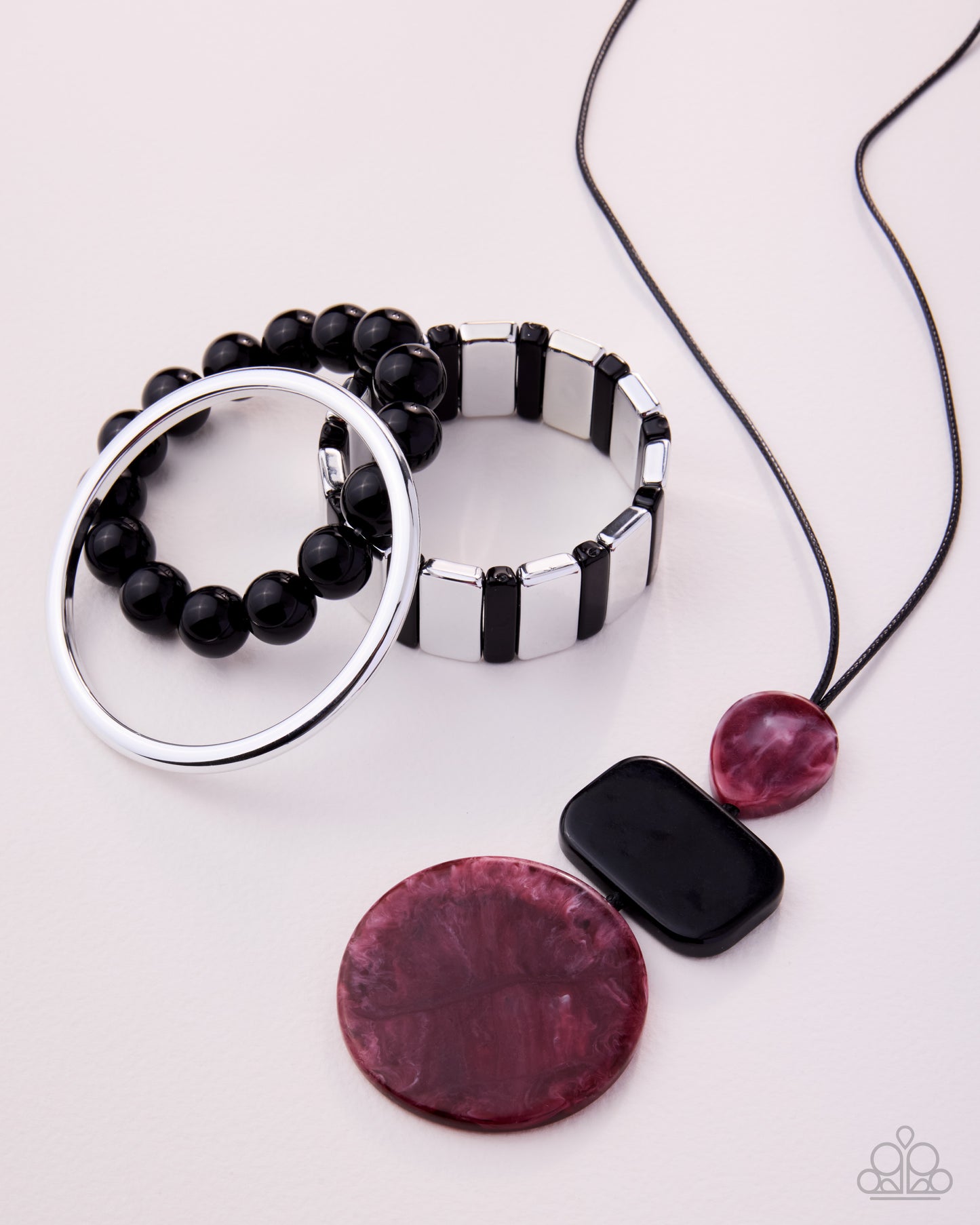 Jewelry set with black beaded bracelet, silver ring, pink and black pendant on a white background