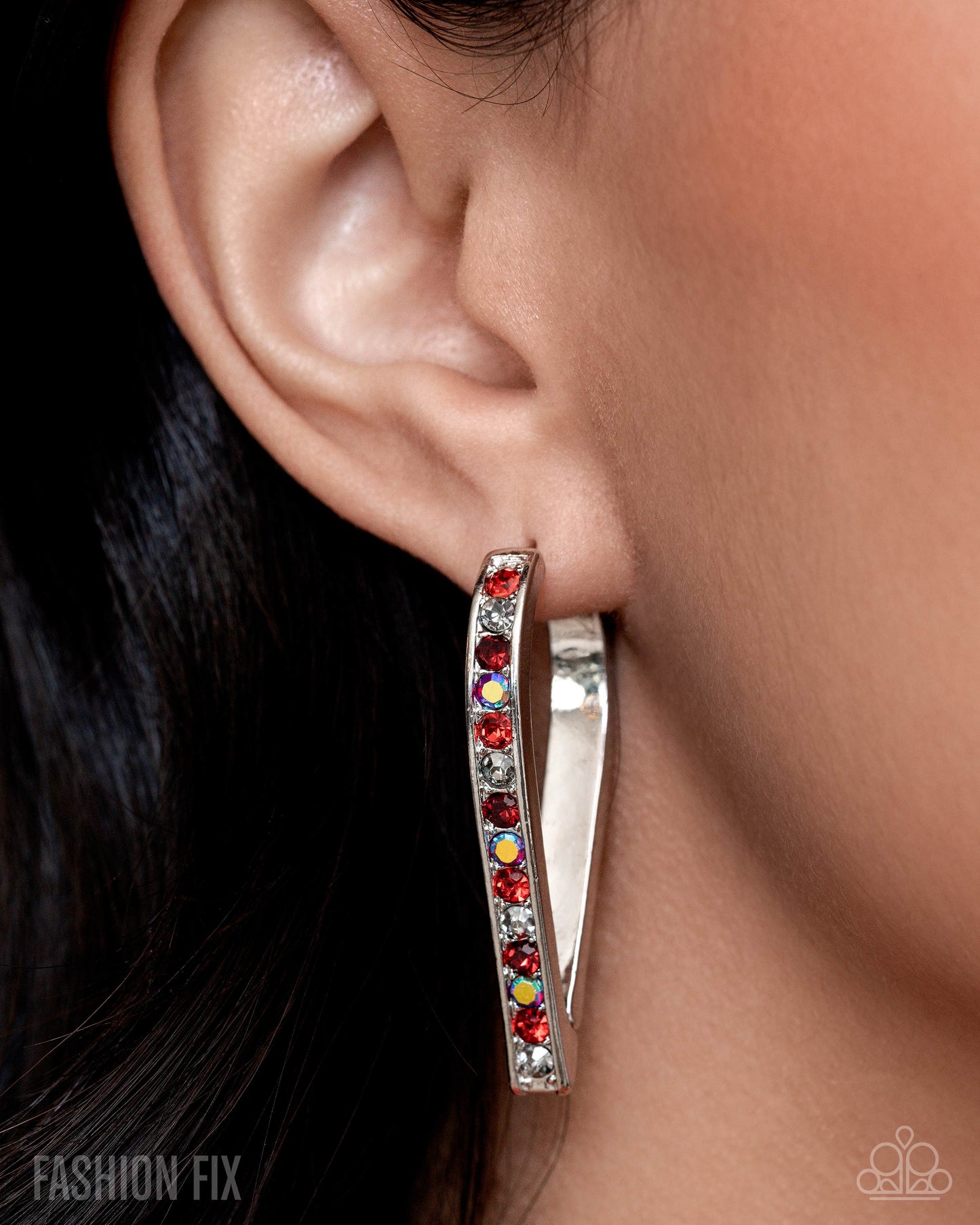 Silver hoop earring with colorful stones worn by a person