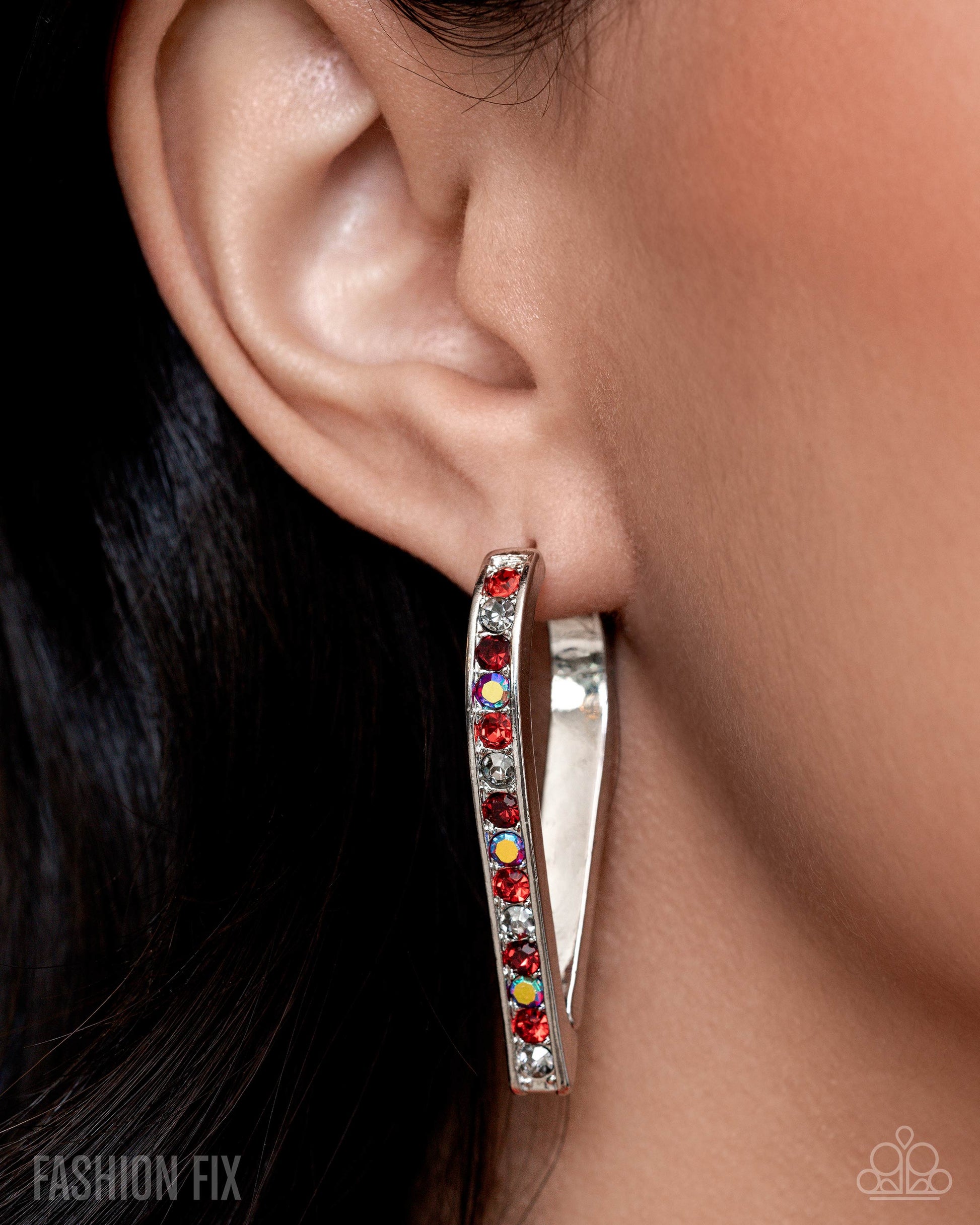 Silver hoop earring with colorful stones worn by a person