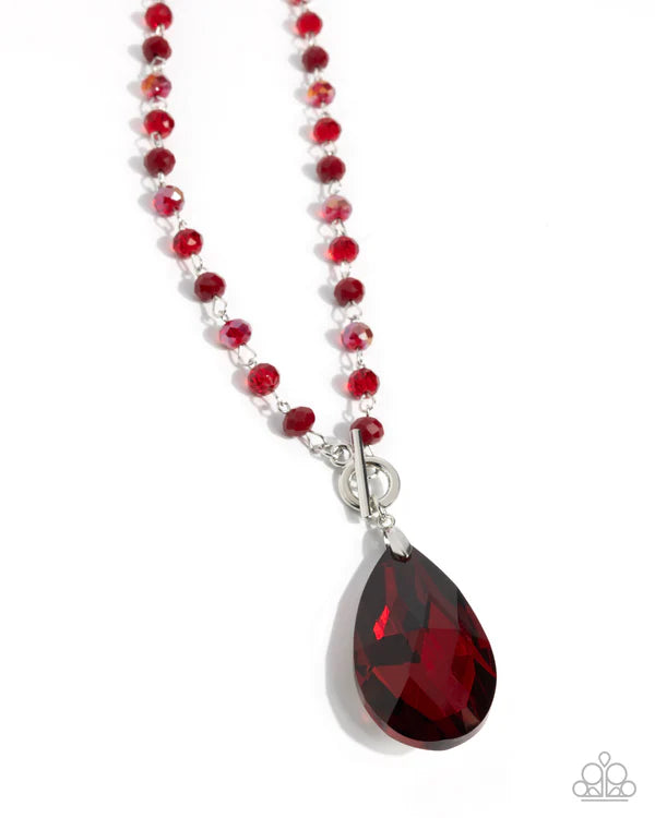 Necklace with red beads and a teardrop-shaped red gemstone pendant on a white background