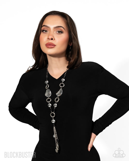 Woman wearing a long, elegant necklace against a white background