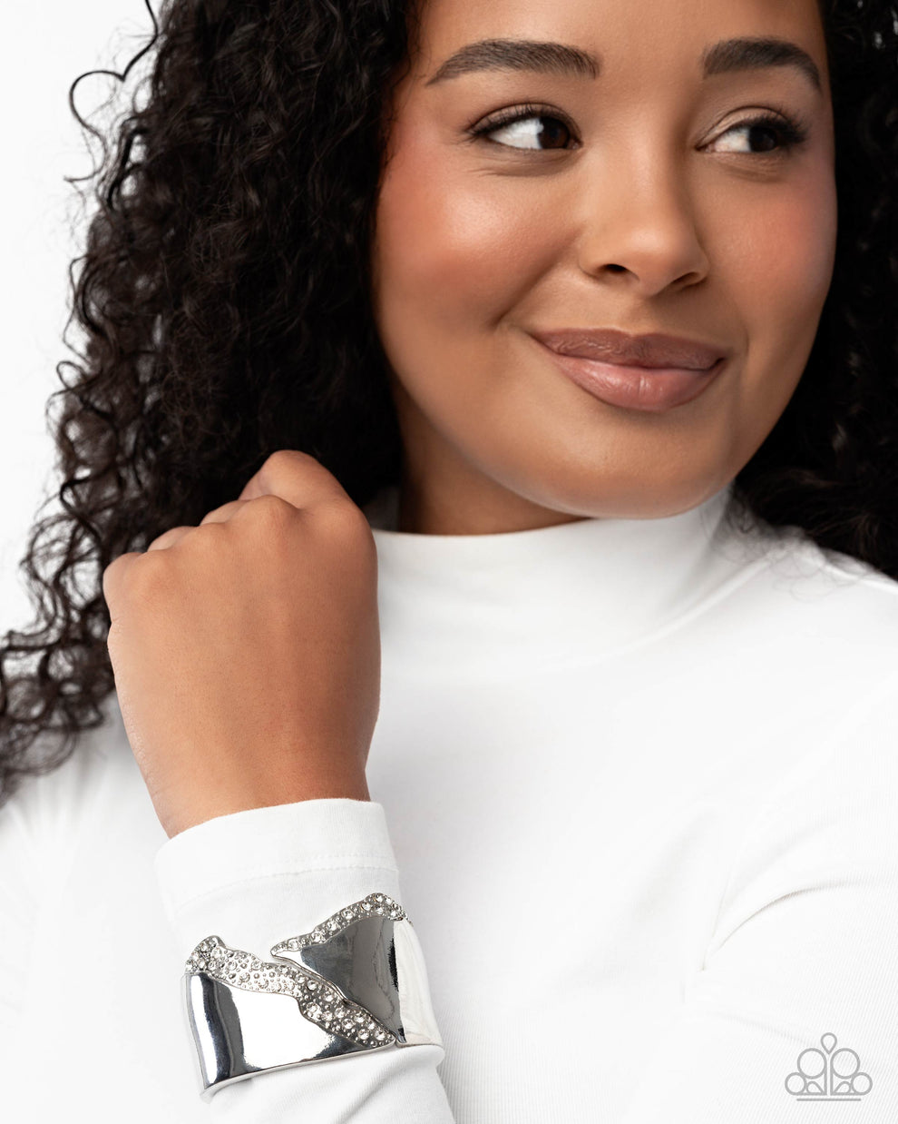 Woman wearing a silver cuff with gemstones on a white background