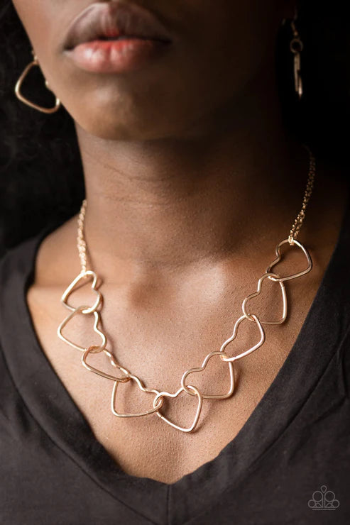Necklace with heart-shaped links worn by a person against a dark background