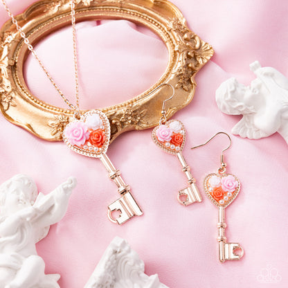 Rose gold key-shaped jewelry set with heart details on a pink background