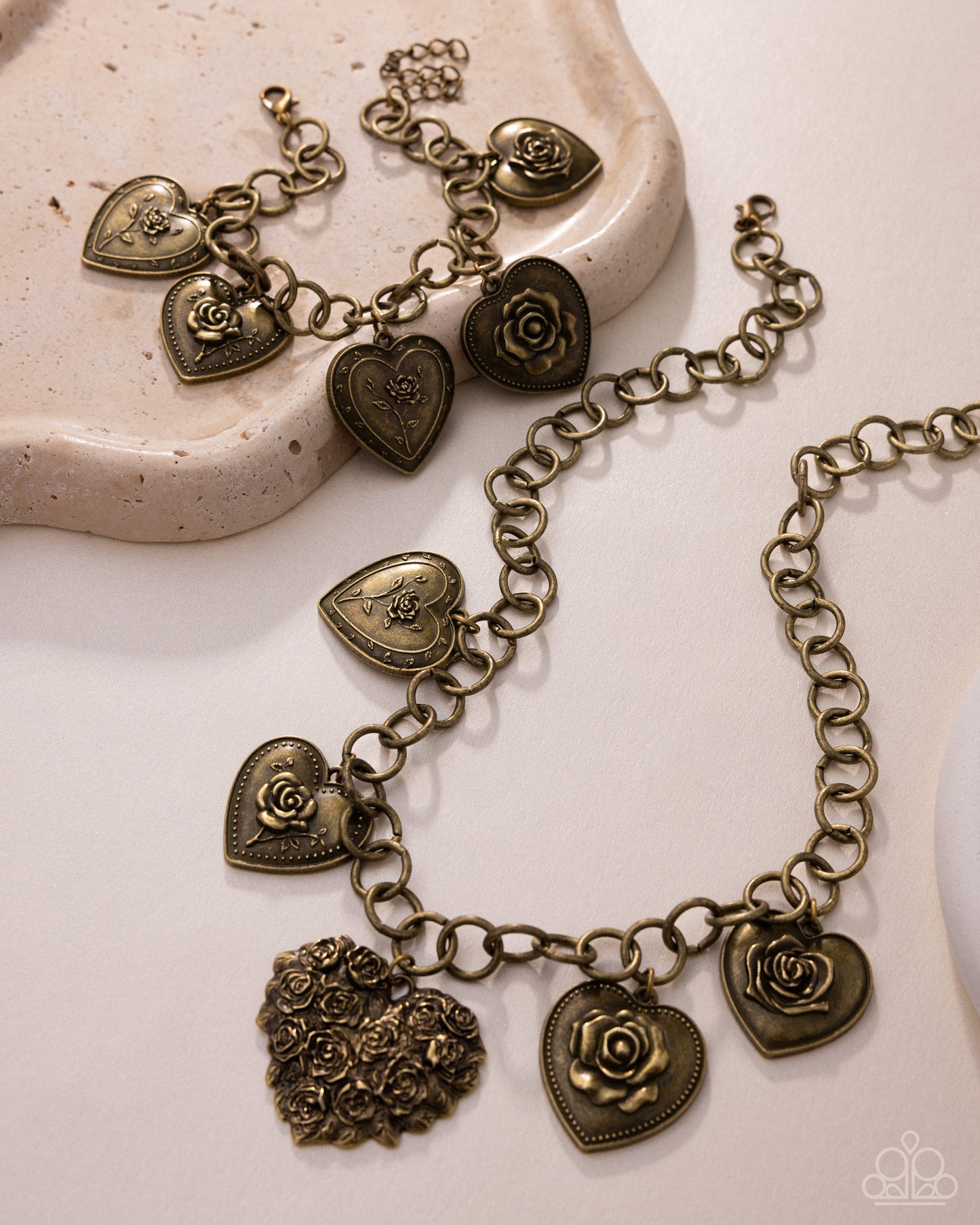 Bronze heart and rose charm bracelet on a textured surface