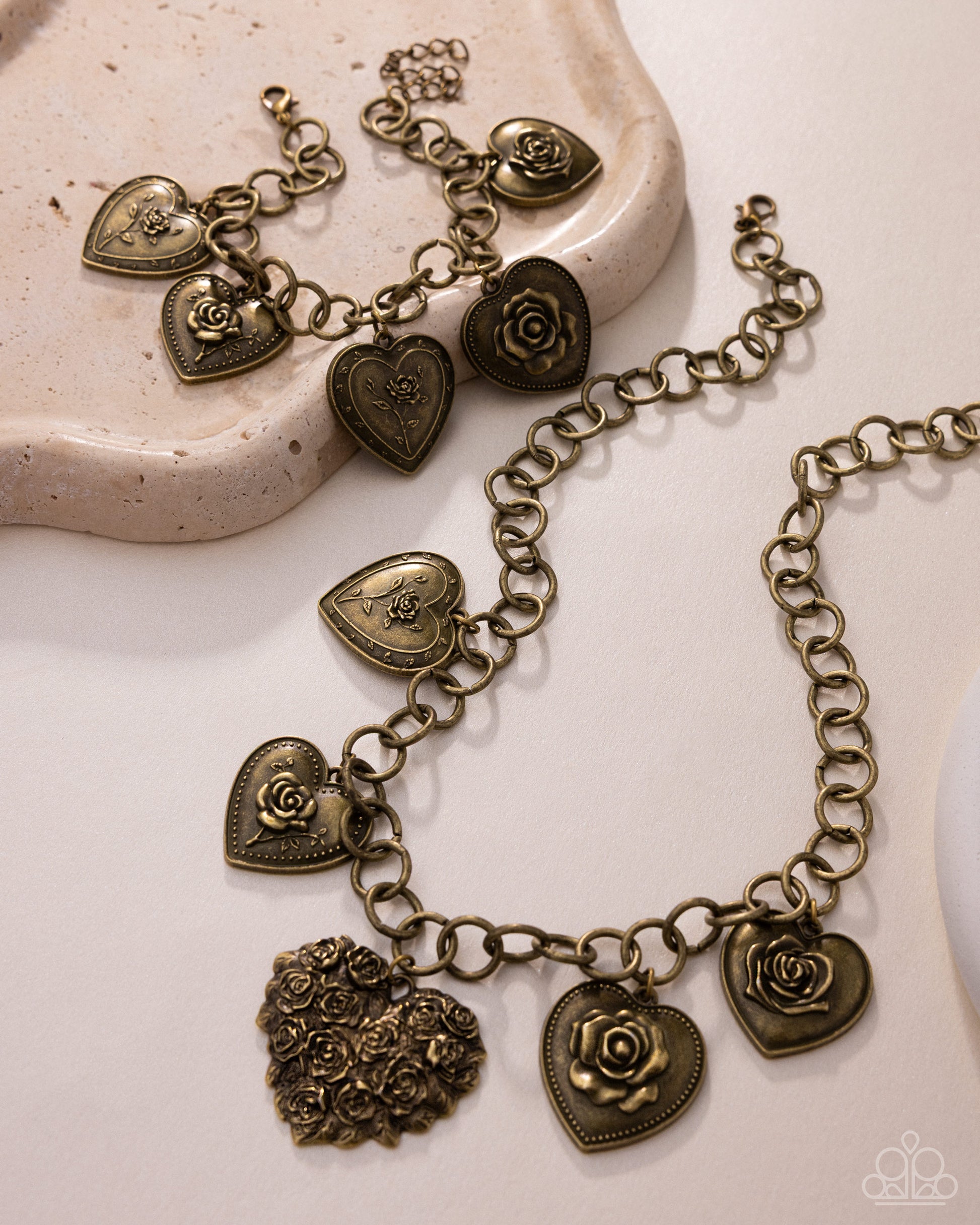Bronze heart and rose charm bracelet on a textured surface