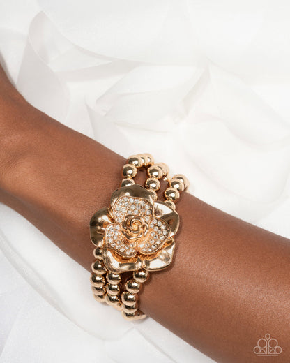 Gold floral bracelet on a wrist with a white background